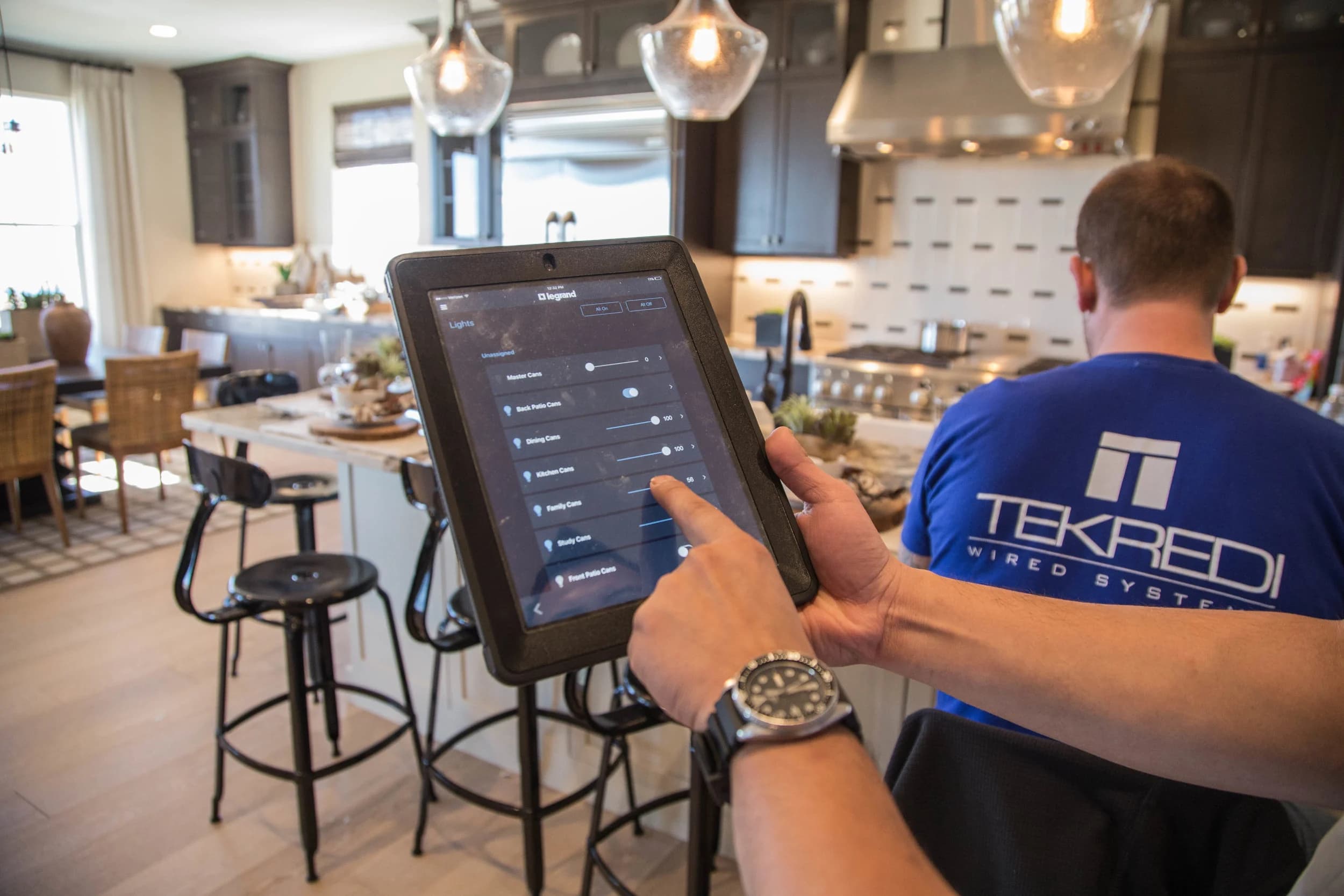 TEKREDI technician controlling a home system from a tablet in the kitchen