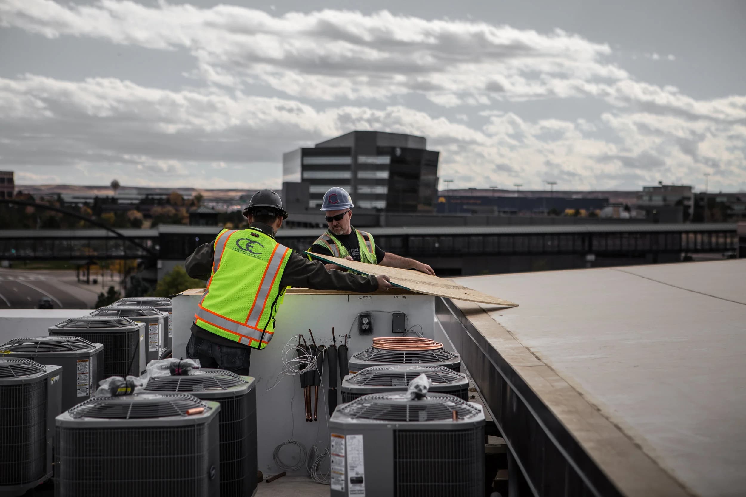 Worker servicing rooftop HVAC condensers
