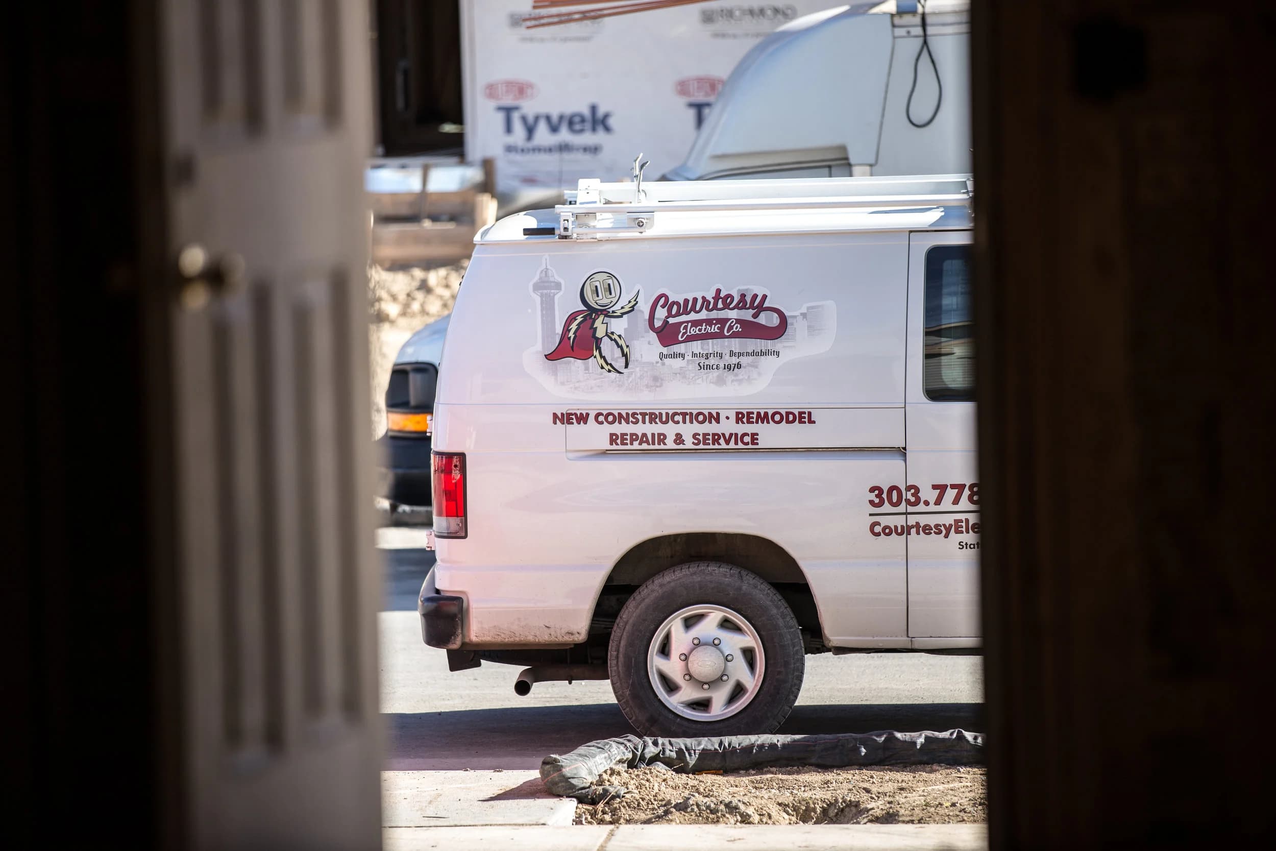 A Courtesy Electric service van parked at a home under construction
